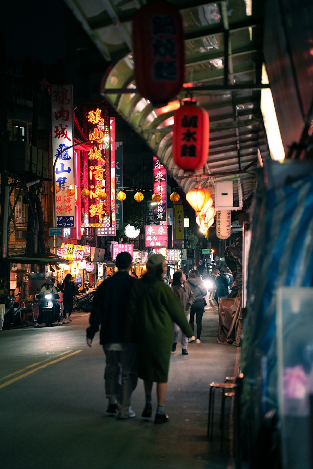 Couple walking down a vibrant, neon-lit street at night