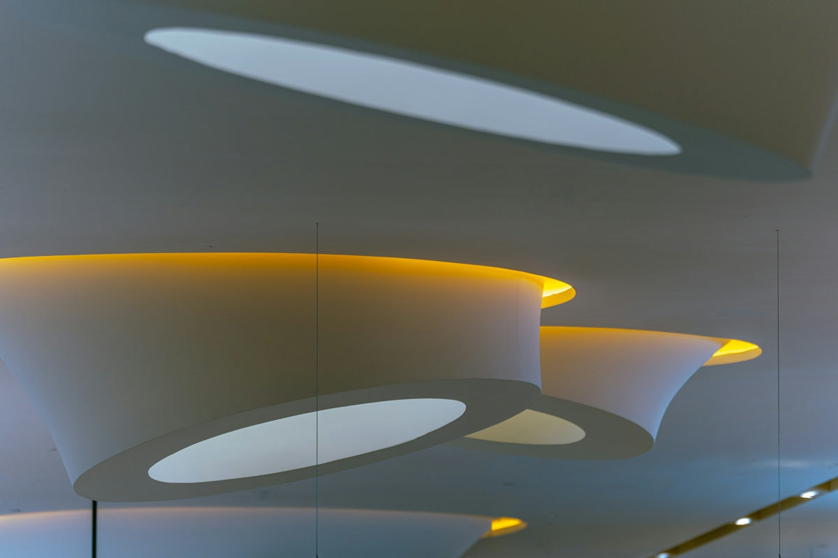 Abstract white ceiling structures with warm yellow recessed lighting